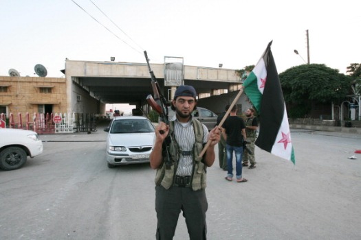 Hatay’ın Reyhanlı ilçesinde Cilvegözü sınır kapısının karşısında bulunan Bab el Hava sınır kapısını ele geçiren muhaliflerden biri elinde Özgür Suriye bayrağını tutarken (ADEM ALTAN/AFP/GettyImages)
