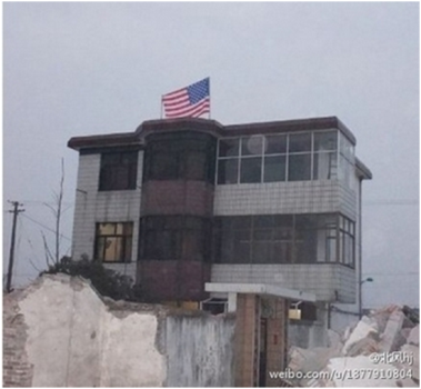 Evinin Yıkılmasını engellemek için, bir Çinli evinin çatısına Amerikan bayrağı dikti. (Ocak 2013) Fotograf: www.epochtimes.com