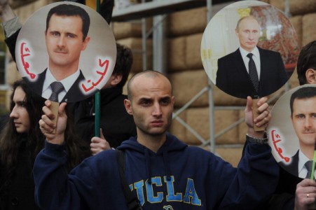 Moskova Amerikan konsolosluğunun önünde bir elinde Suriye Devlet Başkanı Beşar Esad’ın diğer elinde Rusya Başkanı Vladamir Putin’inin fotoğrafını tutan bir protestocu (ANDREY SMIRNOV/AFP/Getty Images)
