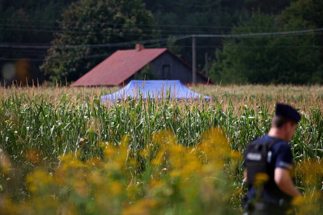 20 Ağustos 2025'te, Polonyalı yetkililere göre, doğu Polonya’daki Osiny köyünde gece saatlerinde tanımlanamayan bir cisim mısır tarlasına düşüp patladıktan sonra, bir polis memuru olay yerindeki polis çadırının yanında yürüyor. (Fotoğraf: Kacper Pempel/Reuters)