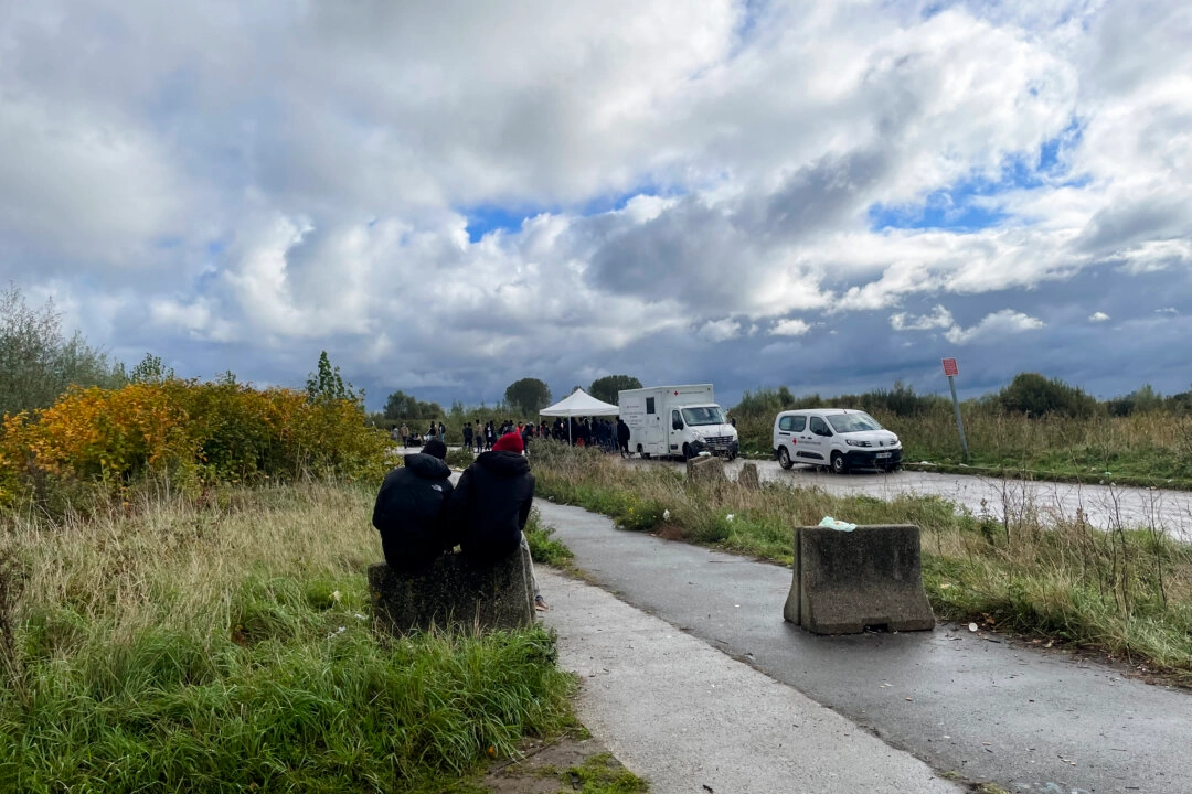 Göçmenler, 15 Ekim 2025’te Fransa'nın Calais kentinde bir Kızıl Haç gıda bankasının önünde oturuyor. (Fotoğraf: Owen Evans / The Epoch Times)
