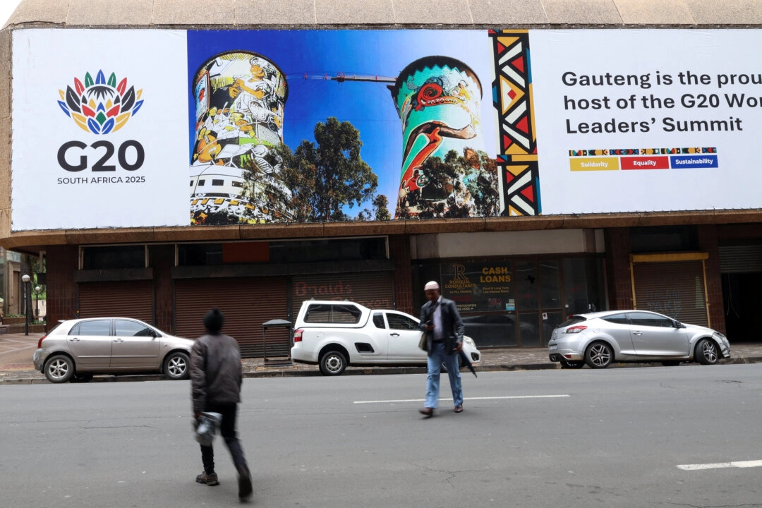 22-23 Kasım 2025 tarihlerinde  Güney Afrika G20 Zirvesi'ni düzenlemeye hazırlanan Johannesburg'da, bir G20 pankartının önünde yürüyor. (Fotoğraf: The Epoch Times aracılığıyla, Siphiwe Sibeko, Reuters)