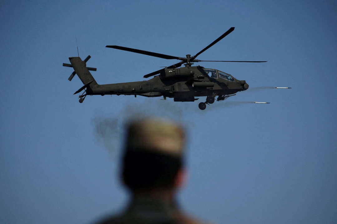 Bir Amerikan askeri, 30 Ekim 2024'te Güney Kore'nin Pocheon kentindeki Rodriguez Canlı Atış Kompleksi'nde, Güney Kore ordusuna ait AH-64E Apache helikopterinin füze fırlatmasını izliyor. Canlı atış tatbikatı, Güney Kore ve ABD orduları arasında ortaklaşa gerçekleştirildi. (Fotoğraf: Kim Hong-Ji/Reuters)