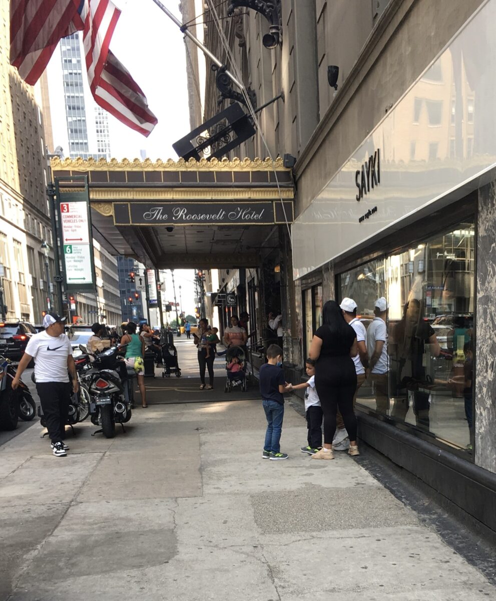Haziran 2023'te New York City'deki Roosevelt Oteli dışında bulunan bir grup göçmen sığınmacı, göçmen krizinin bu aşamasında sığınmacıların barındırıldığı yerdi. (Fotoğraf: Wikimedia)