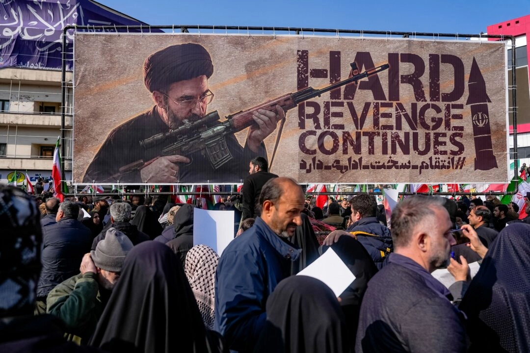Politikacılar İran rejiminin uyuyan hücrelerden olası misilleme eylemleri konusunda Kanada için endişeli.  ABD ve İsrail saldırılarında öldürülen İslam Devrim Muhafızları Ordusu (IRGC) komutan ve askerlerinin cenaze töreni. Arkada, İran rejiminin yeni lideri Ayetullah Mücteba Hamaney’i tasvir eden bir pankart. 11 Mart 2026, Tahran, İran. (Fotoğraf: The Epoch Times aracılığıyla, Khoshiran, AFP - Getty Images)