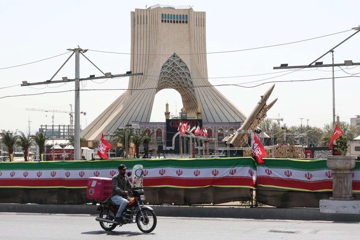 Bir adam, 24 Temmuz 2026’da Tahran’daki Azadi Meydanı’nda sergilenen İran yapımı füzelerin önünden bisikletle geçiyor. AFP/Getty Images.