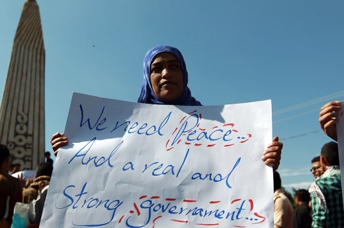 Bir Yemenli kadın Sanaa’daki gösteriler sırasında İngilizce “Barış ve gerçek kuvvetli devlet istiyoruz” yazılı bir pankart açtı (Mohammed Huwais/AFP/Getty Images)