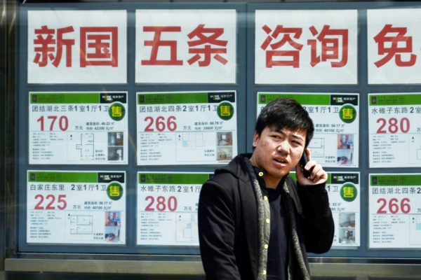 Çinli bir vatandaş 15 Nisan 2013 tarihinde bir emlak bürosunun önünde telefonla konuşuyor. (Wang Zhao/AFP/Getty Images)